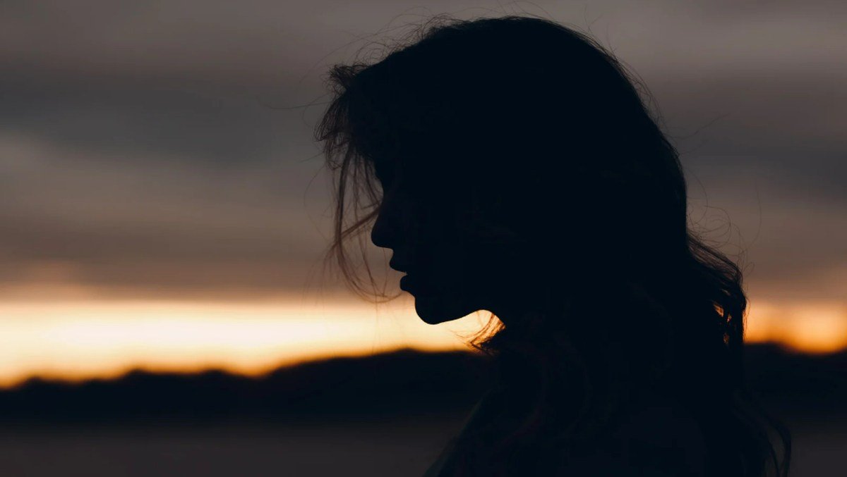 Silhouette of a woman at sunset, symbolizing heartbreak and disbelief in brokenhearted poems