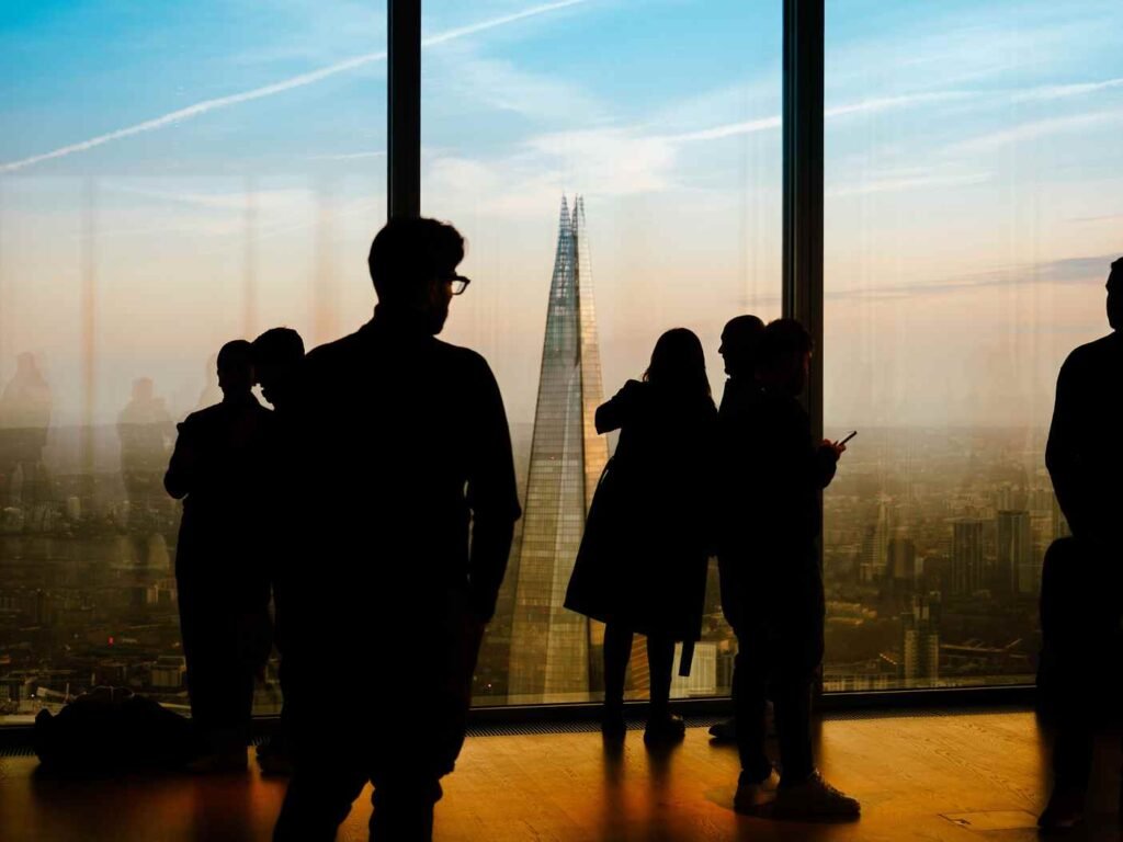 Silhouetted figures standing before a city skyline at dusk, evoking quiet distance and release letting go poem