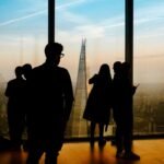Silhouetted figures standing before a city skyline at dusk, evoking quiet distance and release letting go poem
