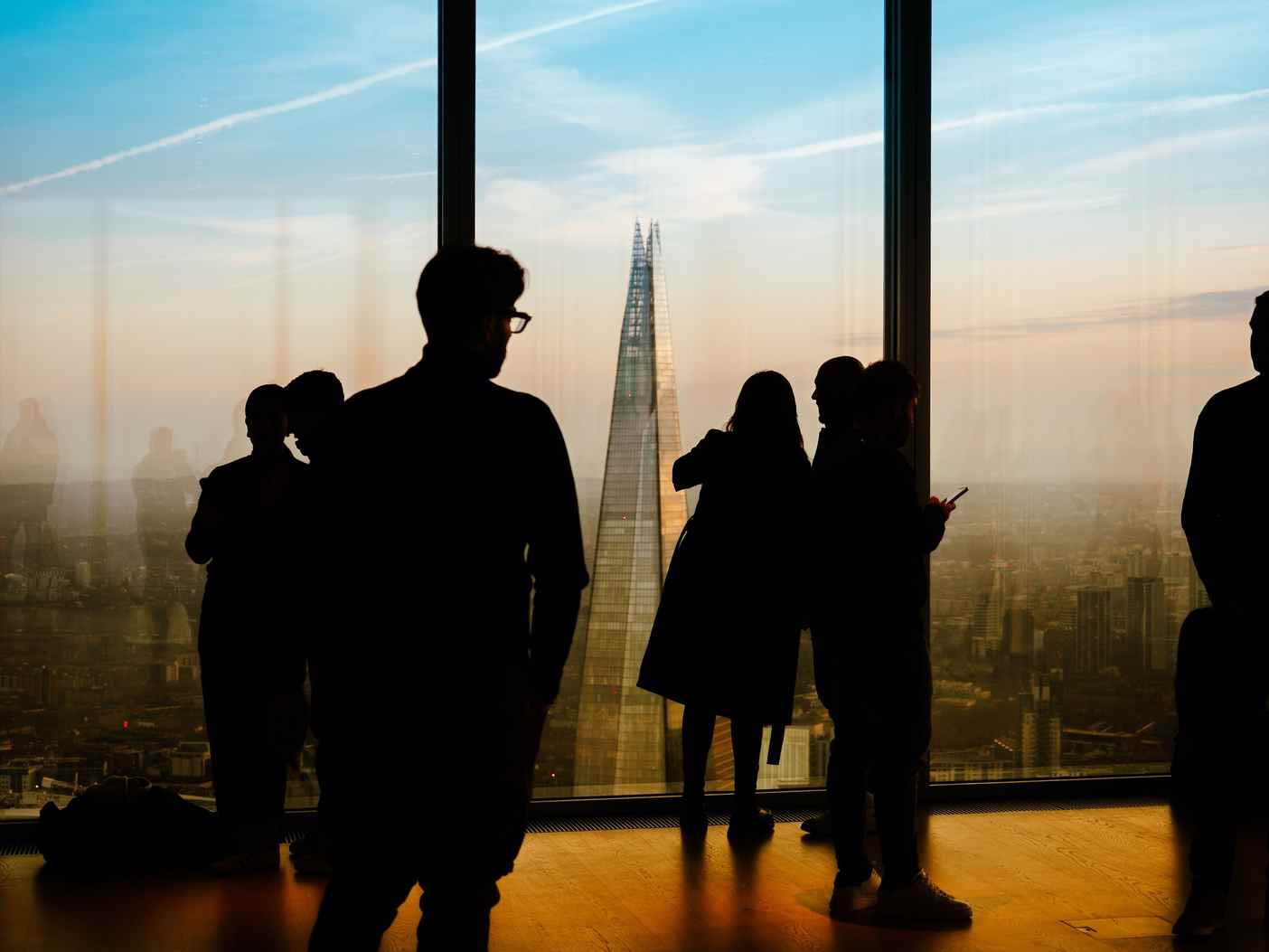 Silhouetted figures standing before a city skyline at dusk, evoking quiet distance and release letting go poem