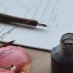 pink roses beside a handwritten poem, pen, and ink bottle — poem on creative inspiration